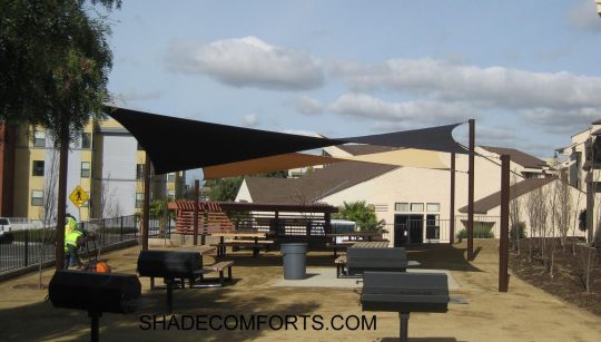 See photo of a tensile shade structure over a courtyard patio in Alameda County. Two hypar shade sails provide the protective cover.