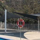 This photo shows a shade sails structure on the deck beside a Los Angeles swimming pool.