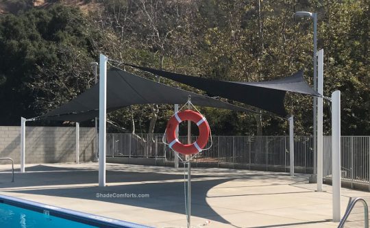 This photo shows a shade sails structure on the deck beside a Los Angeles swimming pool.