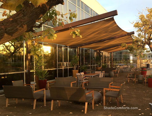 Commercial shade sails cover a corporate patio with a custom design