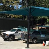 This fabric shade canopy protects maintenance vehicles from UV damage at this municipal corporate yard. The sun used to break down the rubber hoses and gaskets, which rendered the trucks undependable when needed for emergencies.