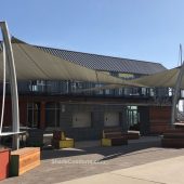 These commercial shade sails cover the walkway at a San Diego office and retail center. Each of the 3 posts are curved to match the nautical theme of sailing ships.