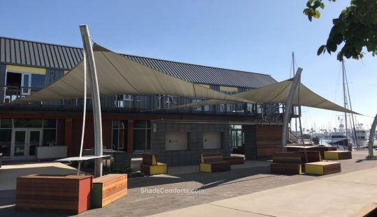 These commercial shade sails cover the walkway at a San Diego office and retail center. Each of the 3 posts are curved to match the nautical theme of sailing ships.