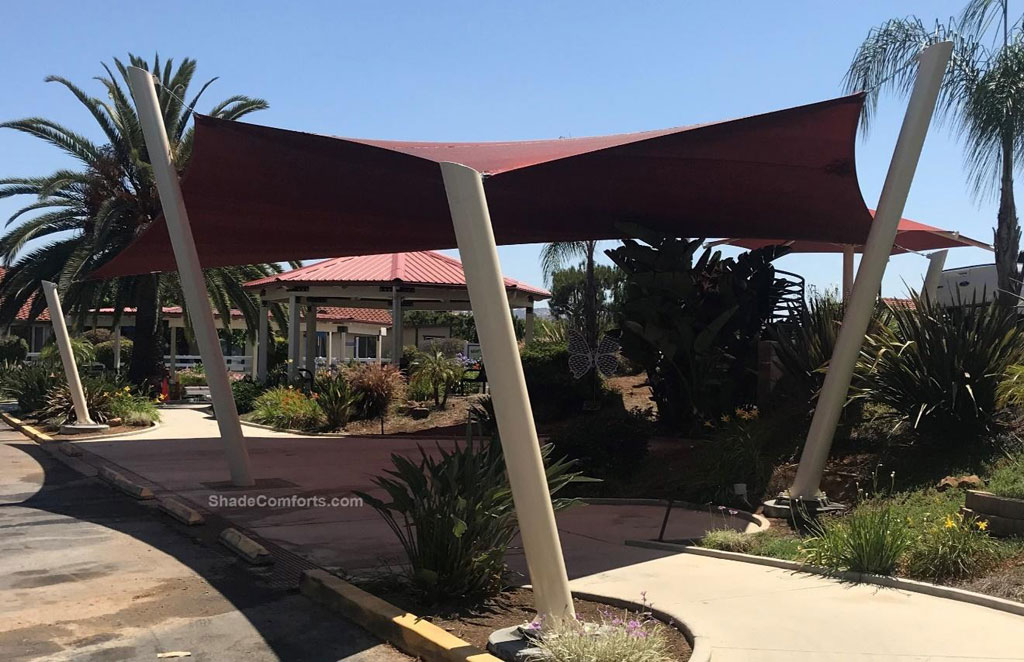 This hypar shade sail structure cools the shuttle bus waiting area at Mountain Shadows Community Home San Marco, CA, a San Diego suburb. County.  Its posts lean outwards by 15-degrees.