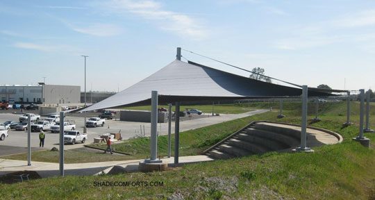 See photo of a tensile shade structure covering bleachers at a Sacramento company. Four hypar sail fabrics create permanent outdoor sun protection.