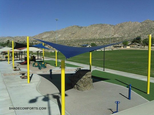 See photo of tensile shade structures covering a San Bernardino County playground. Each hypar shade sail is 30’x30’.