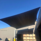 Tensioned fabric shade structure connects to building wall.