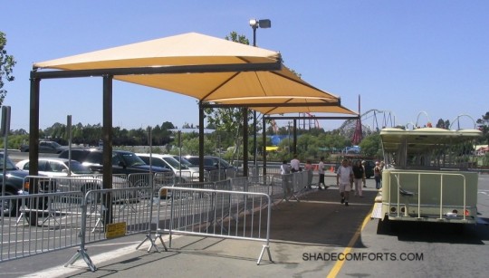 shuttle stop shade structure keeps passengers cool while awaiting minibus pickup. The fabric canopies cover the entire waiting area.