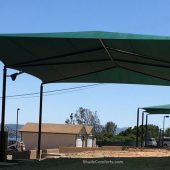 This volleyball court shade structure (shown in foreground) is in Lake County, CA. It measures 80’x50’ with a 20’ clearance height. One 4,000 square foot fabric is tensioned on hip framing atop (6) posts.